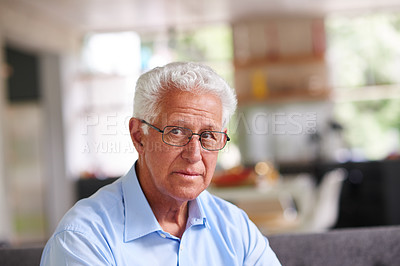 Buy stock photo Shot of a thoughtful looking senior man sitting on his sofa