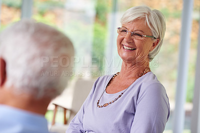 Buy stock photo Home, senior couple and smile in living room with conversation, bonding and support. People, relationship and happy or laughing as pensioners on retirement on couch on break for love, care and trust