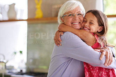 Buy stock photo Portrait of a cute little girl hugging her grandmother in a kitchen
