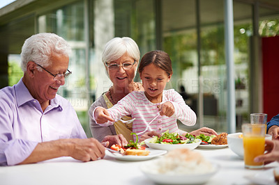 Buy stock photo Shot of a granddaughter sitting with her grandparents while enjoying a meal outside