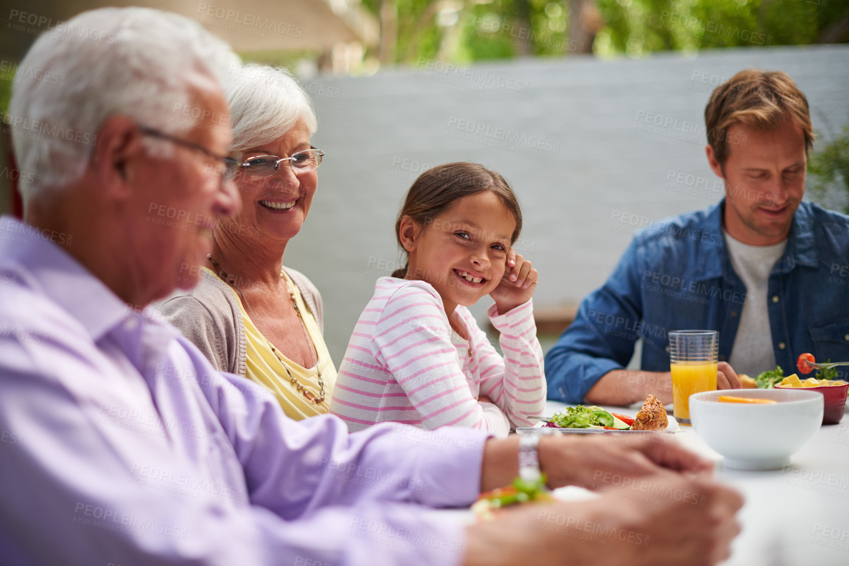 Buy stock photo Shot of a happy multi-generational family having a meal together outside