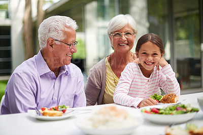 Buy stock photo Shot of a granddaughter sitting with her grandparents while enjoying a meal outside