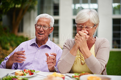 Buy stock photo Shot of a happy senior couple laughing while enjoying a meal on their patio