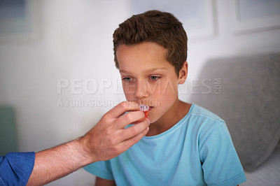 Buy stock photo Shot of a caring father giving his sick little boy some medicine at home