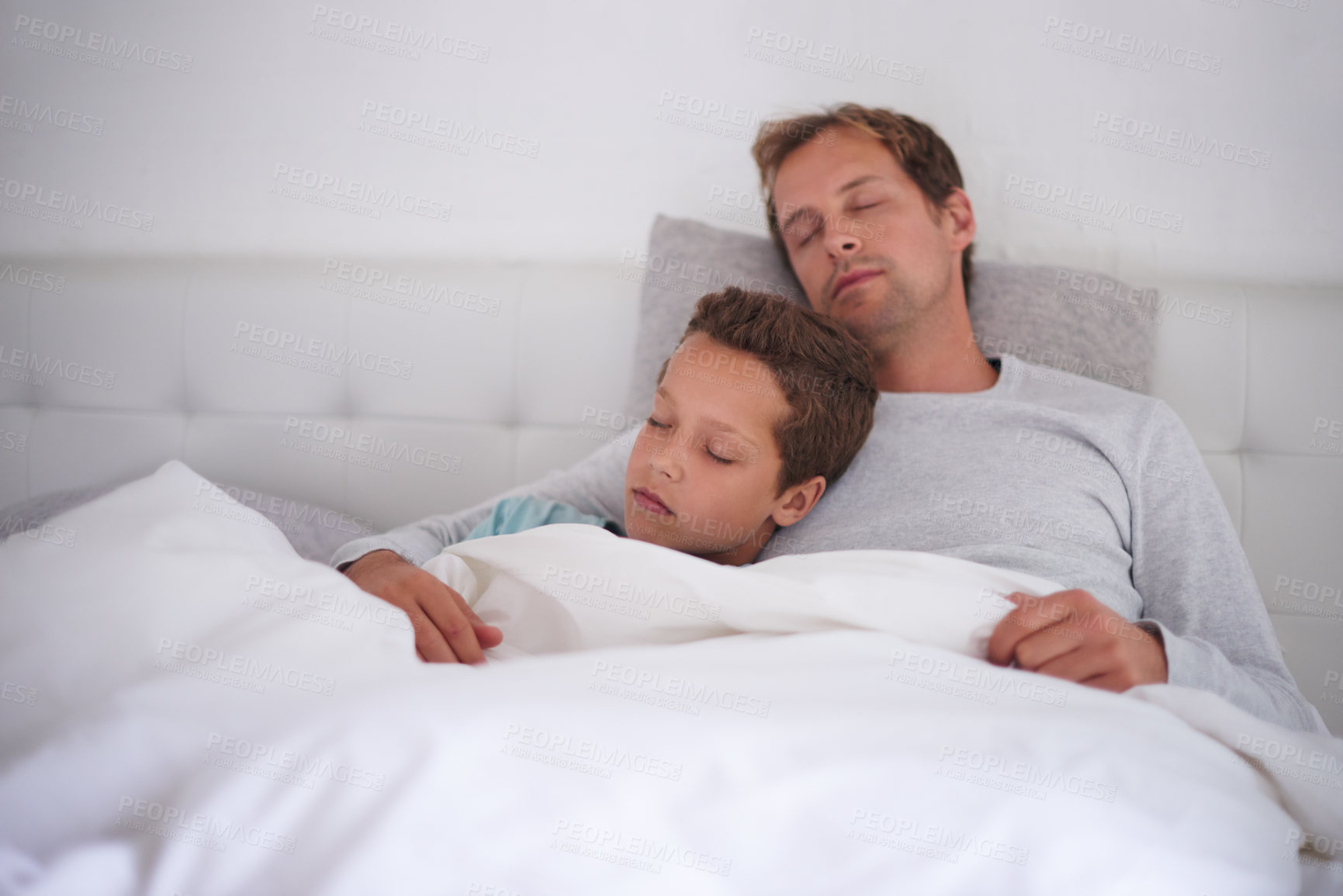 Buy stock photo Father, sleeping and hug son in home, love and support child in dream or nap for comfort. Dad, boy and embrace kid for peace or security in rest, care and exhausted family for bonding in bedroom