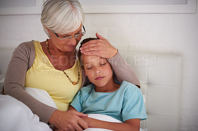 Buy stock photo Shot of a caring grandmother taking care of her sick grandson at home