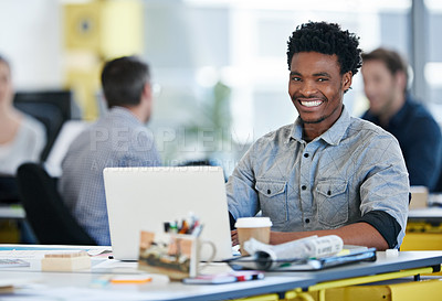 Buy stock photo Portrait of a designer sitting at his desk working on a laptop with colleagues in the background