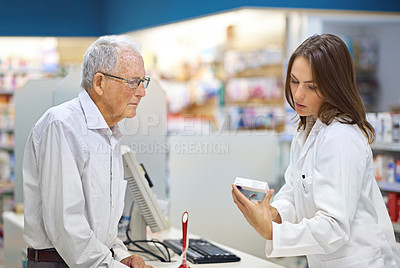 Buy stock photo Shot of a young pharmacist helping an elderly customer at the prescription counter