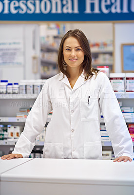 Buy stock photo Portrait of an attractive young pharmacist standing at the prescription counter