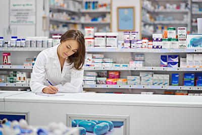 Buy stock photo Shot of an attractive young pharmacist working at the prescription counter