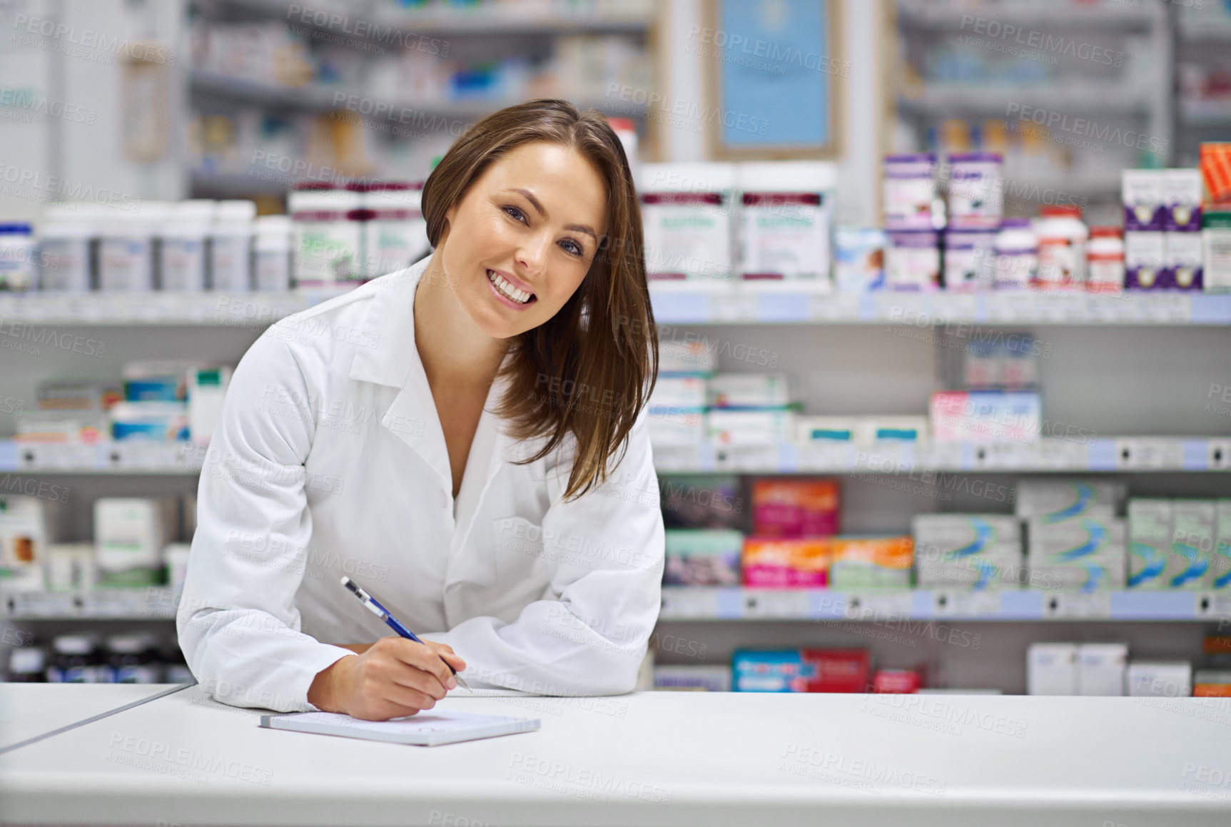 Buy stock photo Portrait of an attractive young pharmacist standing at the prescription counter