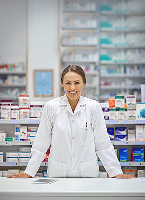 Buy stock photo Portrait of an attractive young pharmacist standing at the prescription counter