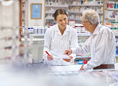 Buy stock photo Shot of a young pharmacist helping an elderly customer at the prescription counter