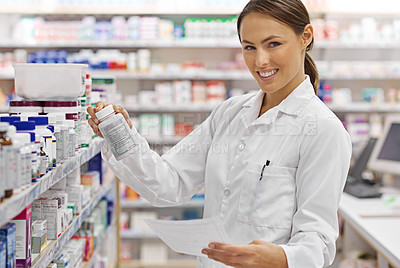 Buy stock photo Shot of an attractive young pharmacist checking stock in an aisle