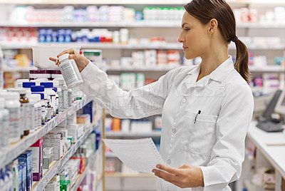 Buy stock photo Shot of an attractive young pharmacist checking stock in an aisle