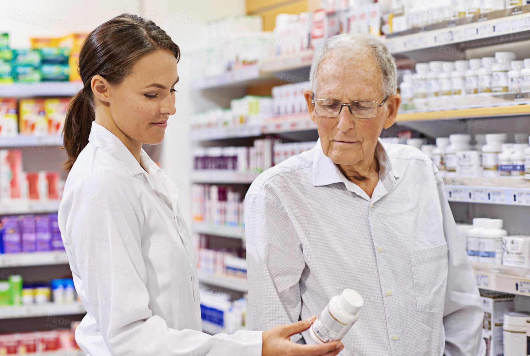 Buy stock photo Shot of a young pharmacist helping an elderly customer