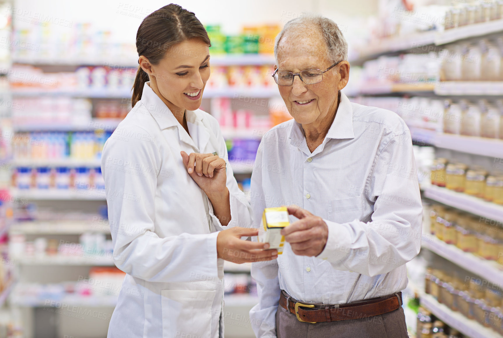 Buy stock photo Shot of a young pharmacist helping an elderly customer