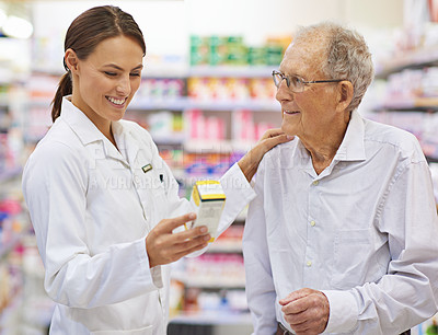 Buy stock photo Shot of a young pharmacist helping an elderly customer with his prescription