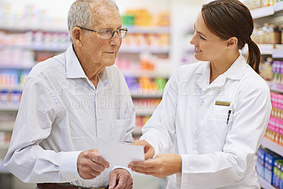 Buy stock photo Shot of a young pharmacist helping an elderly customer with his prescription