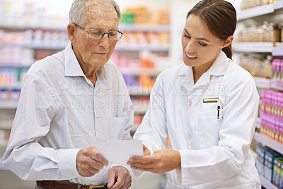 Buy stock photo Shot of a young pharmacist helping an elderly customer with his prescription