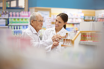 Buy stock photo Shot of a young pharmacist helping an elderly customer