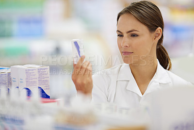 Buy stock photo Shot of an attractive young pharmacist collecting a prescription in an aisle