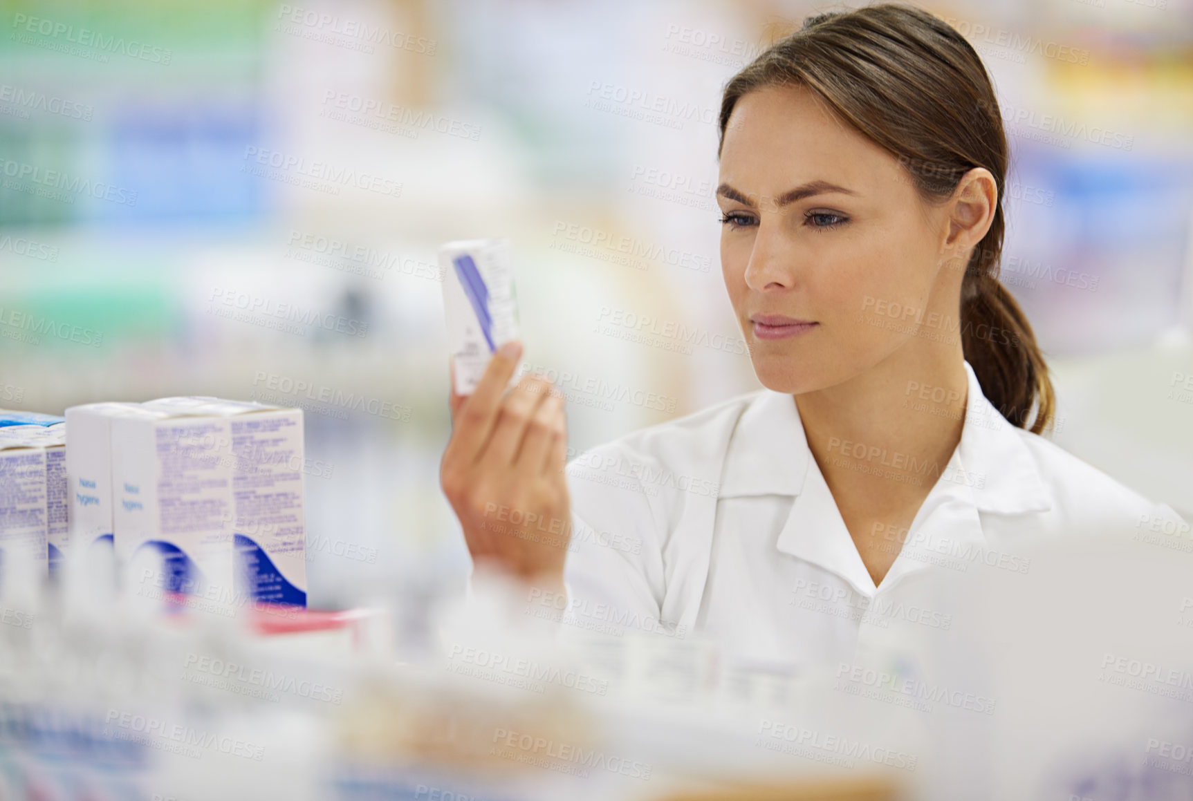 Buy stock photo Shot of an attractive young pharmacist collecting a prescription in an aisle