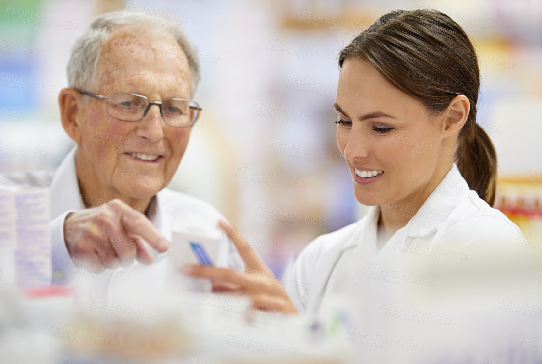 Buy stock photo Shot of a young pharmacist helping an elderly customer