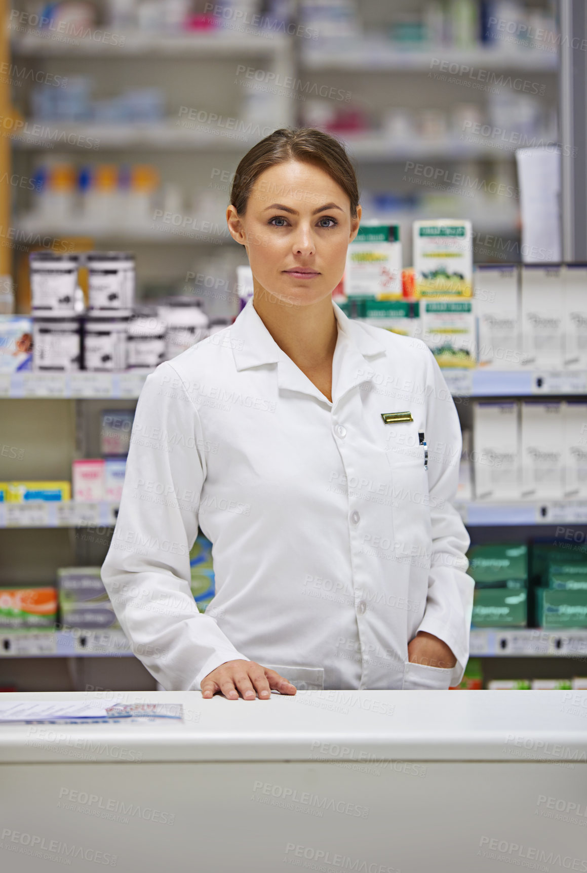 Buy stock photo Portrait of an attractive young pharmacist standing at the prescription counter