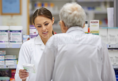 Buy stock photo Shot of a young pharmacist helping an elderly customer