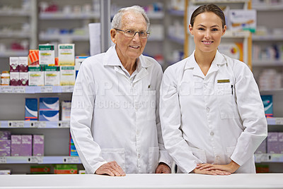 Buy stock photo Shot of an elderly pharmacist and a young pharmacist standing at counter