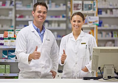 Buy stock photo Portrait of  two pharmacists standing at a counter giving the thumbs up