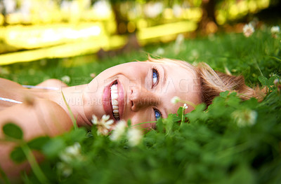 Buy stock photo Spring, happy and calm with woman on grass in nature for relax, smile and peace. Park, flowers and field with face of female person lying in countryside meadow for summer, vacation and wellness