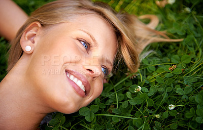 Buy stock photo Spring, happy and field with woman on grass in nature for calm, smile and peace. Park, flowers and relax with face of female person lying in countryside meadow for summer, vacation and wellness