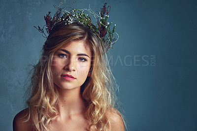 Buy stock photo Cropped shot of a young woman posing with flowers in her hair against a blue background