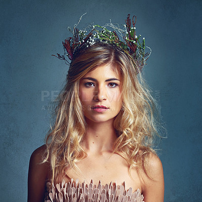 Buy stock photo Cropped shot of a young woman posing with flowers in her hair against a blue background