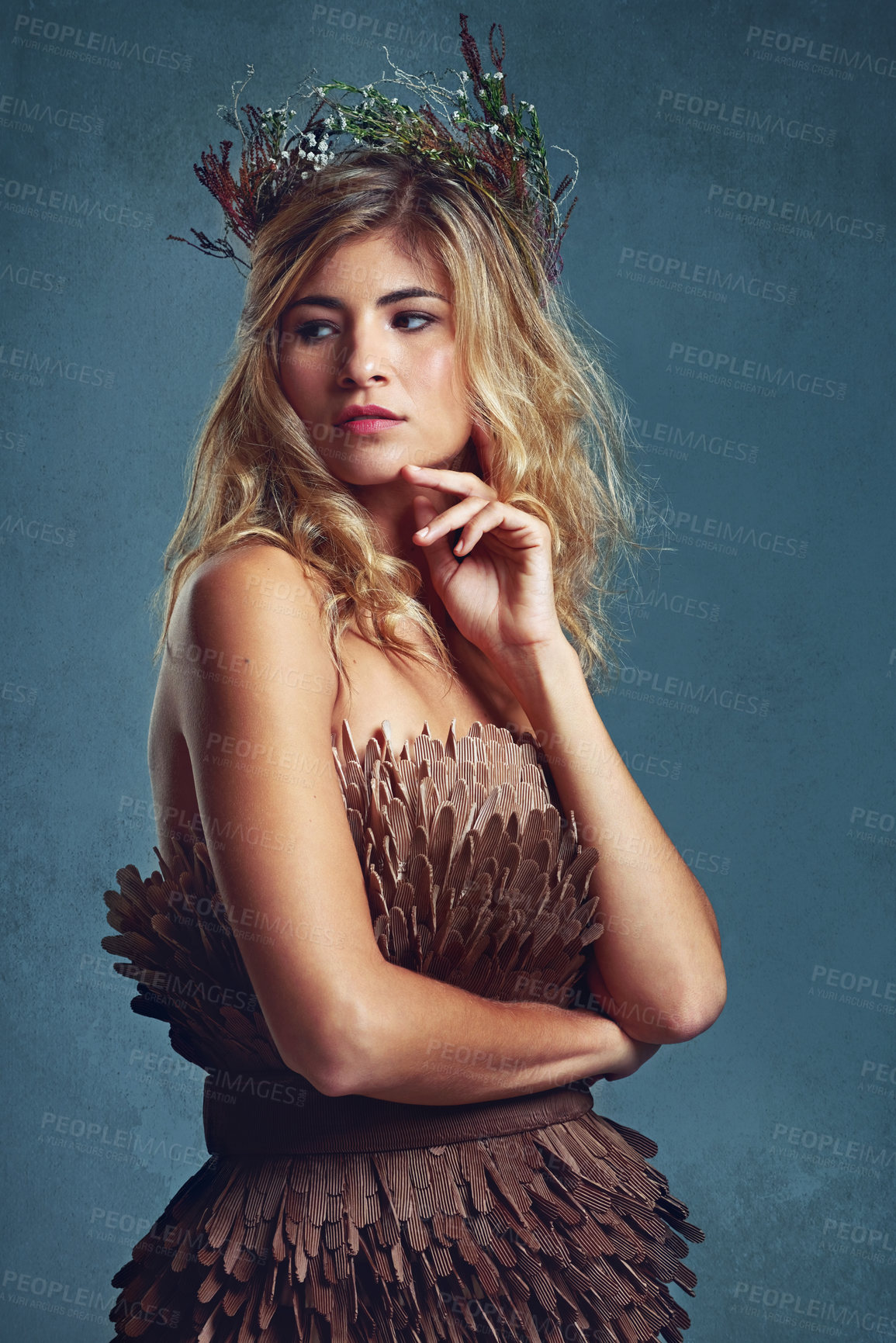 Buy stock photo Cropped shot of a young woman posing with flowers in her hair against a blue background