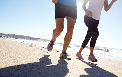 Buy stock photo Shot of a young couple jogging together on the beach
