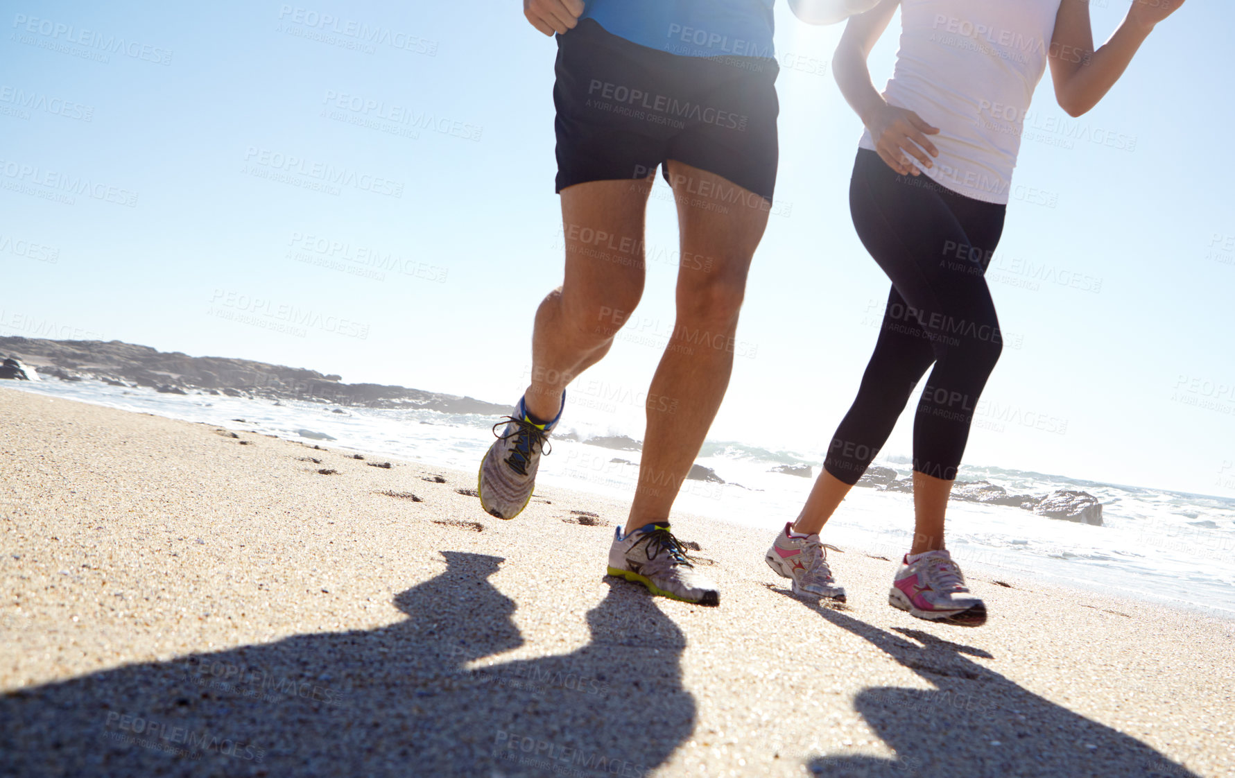 Buy stock photo Shot of a young couple jogging together on the beach