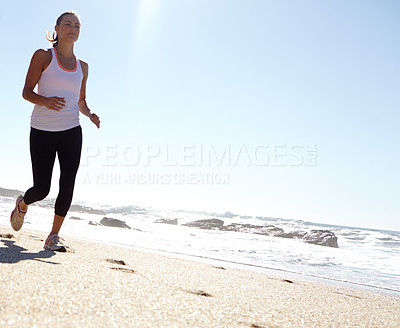 Buy stock photo Shot of a young woman taking a jog on the beach