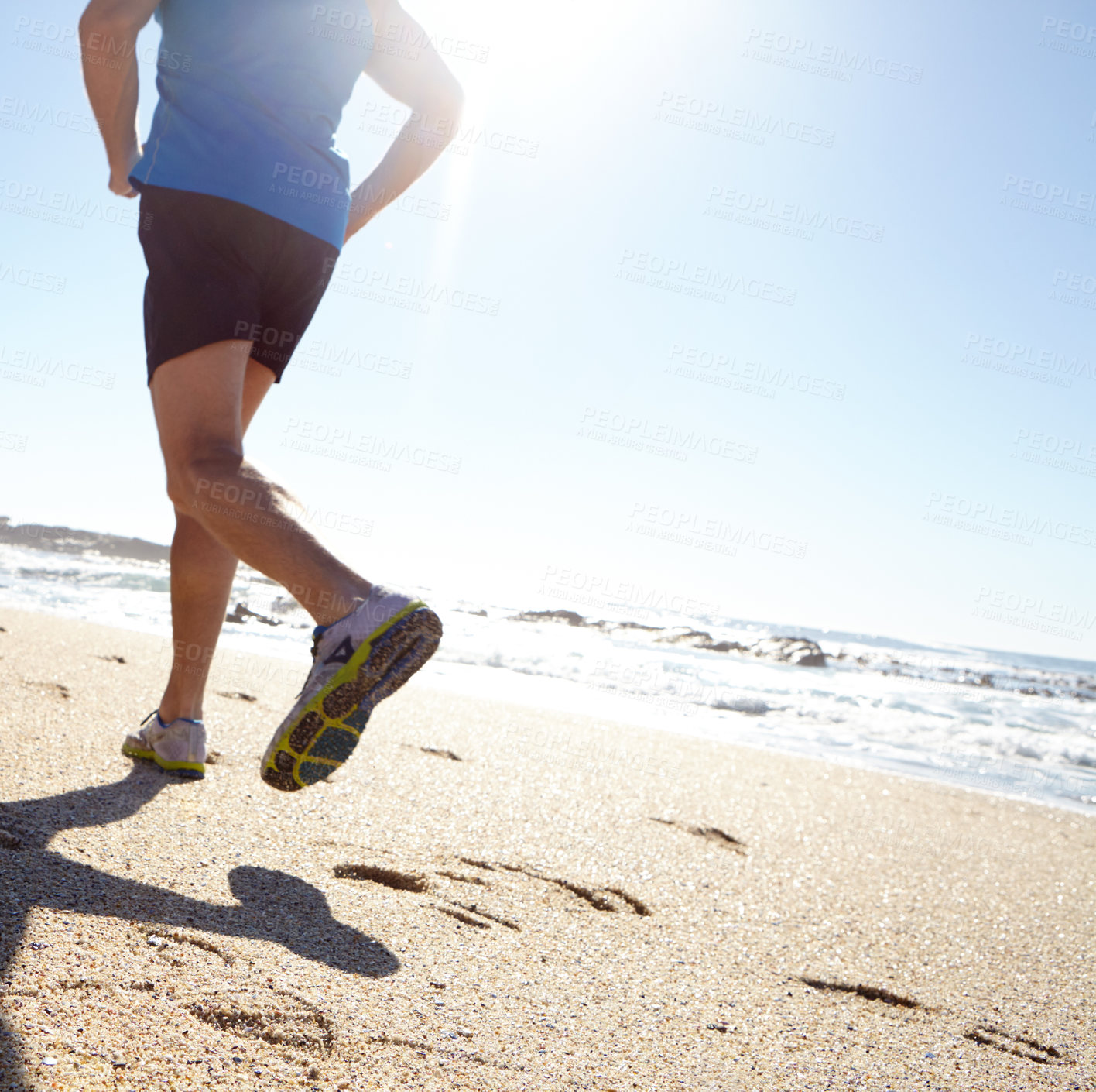 Buy stock photo Rearview shot of a man taking a jog by the beach