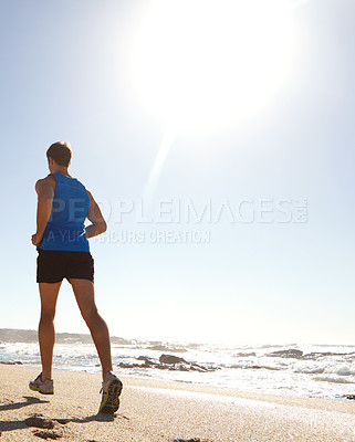 Buy stock photo Rearview shot of a man taking a jog by the beach