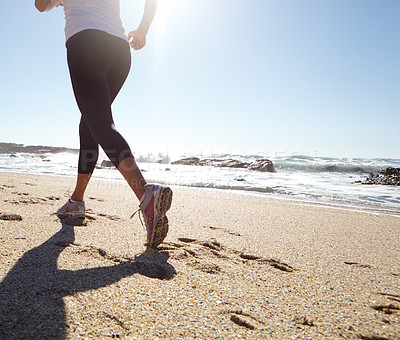 Buy stock photo Shot of a young woman jogging on the beach