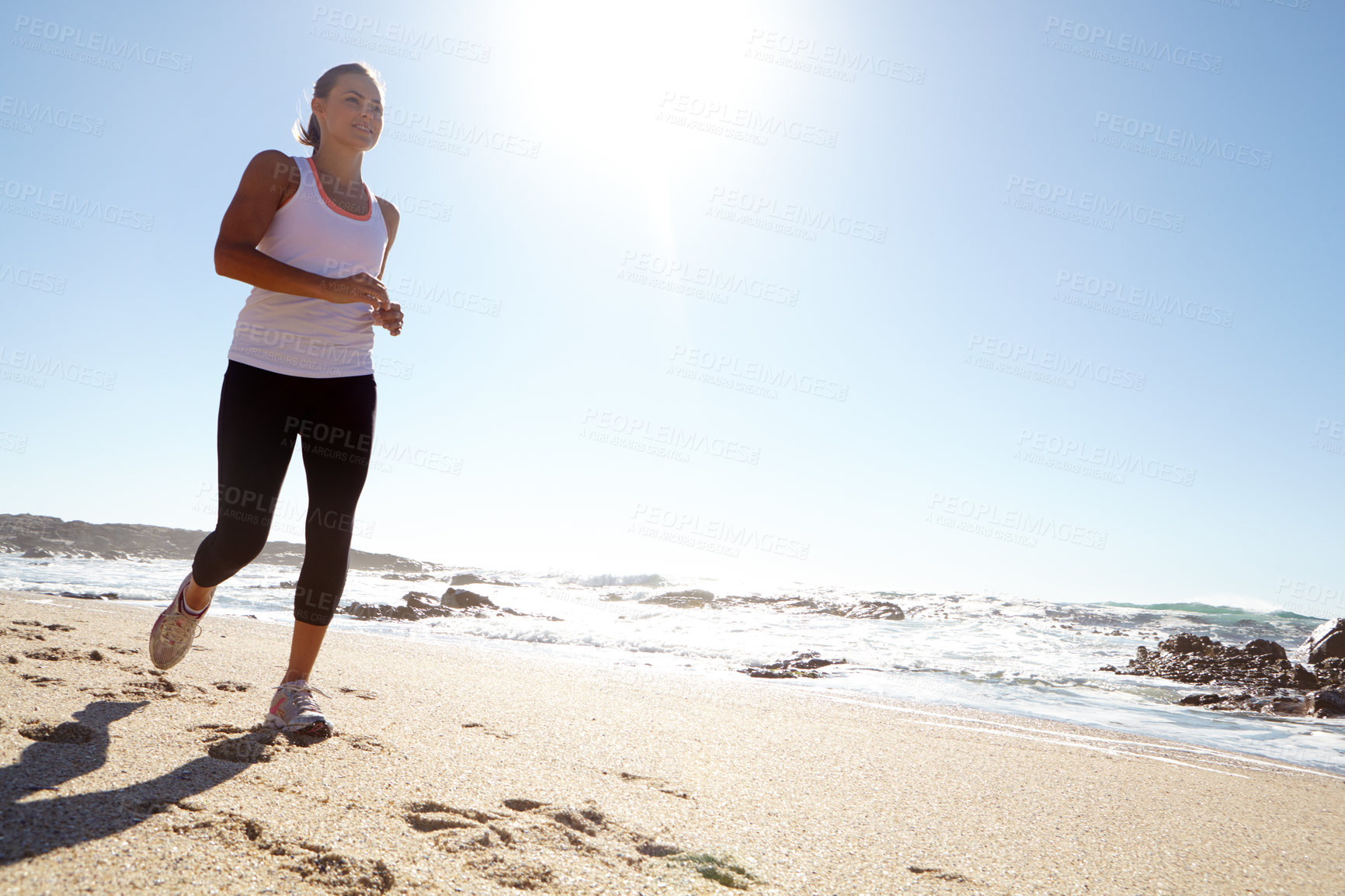 Buy stock photo Shot of a young woman jogging on the beach