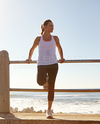 Buy stock photo Shot of a woman resting after a long jog by the beach