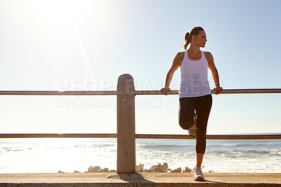 Buy stock photo Shot of a woman resting after a long jog by the beach