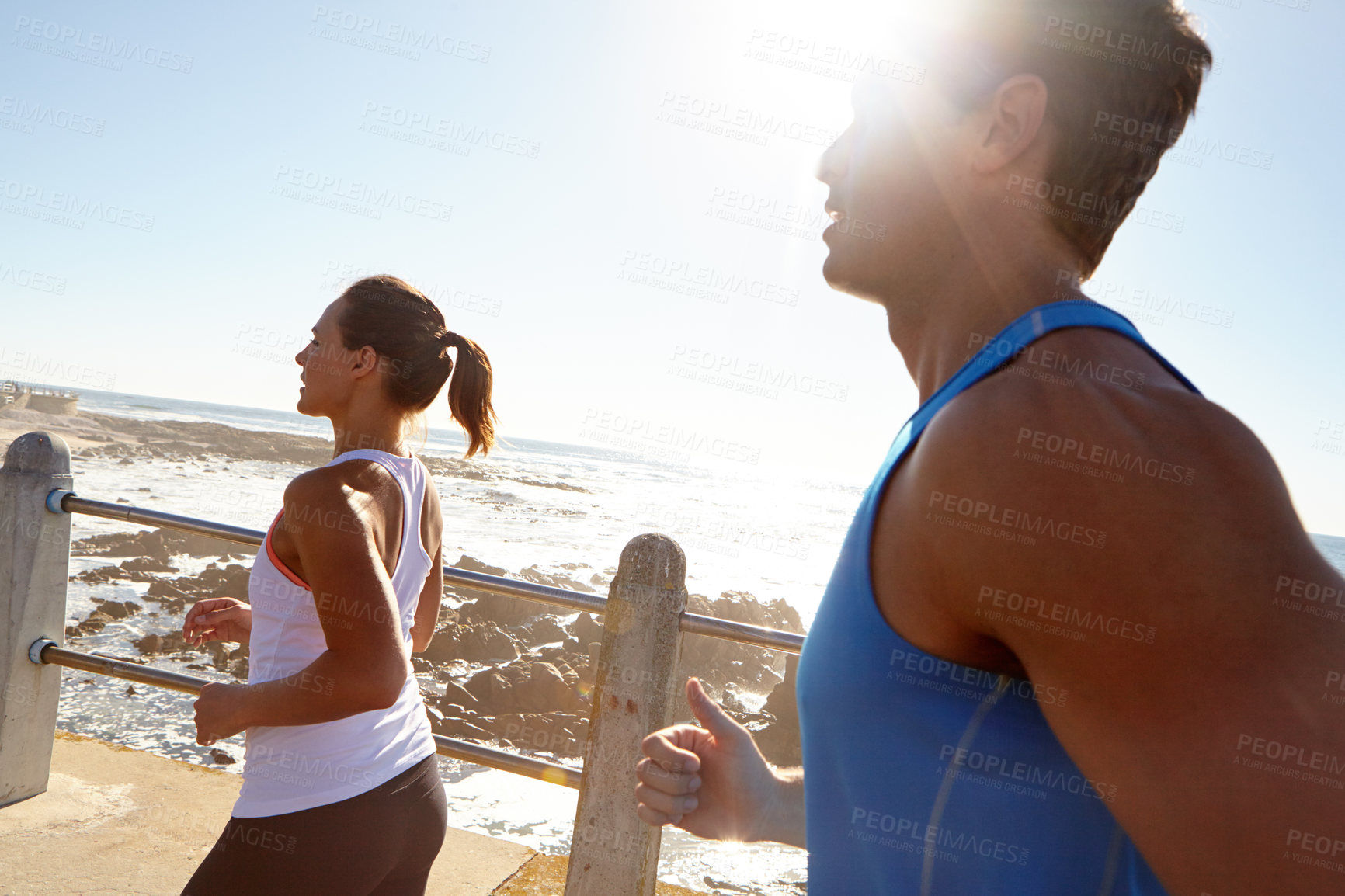 Buy stock photo Shot of a young couple jogging together on the promenade 