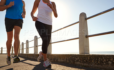 Buy stock photo Cropped shot of two people jogging on the promenade