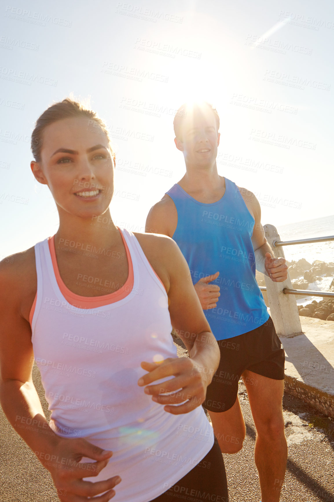 Buy stock photo Shot of a young couple jogging together on the promenade 