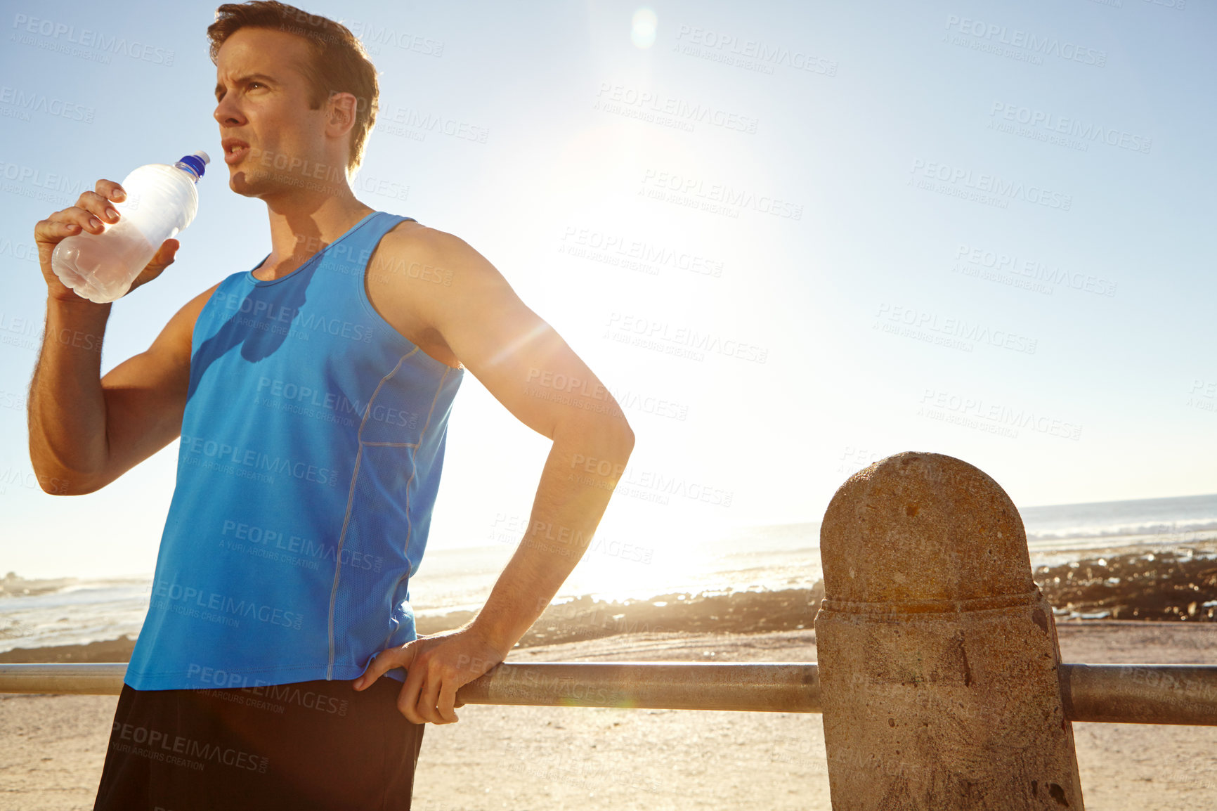 Buy stock photo Shot of a man holding a bottle of water and taking a break after a long jog 